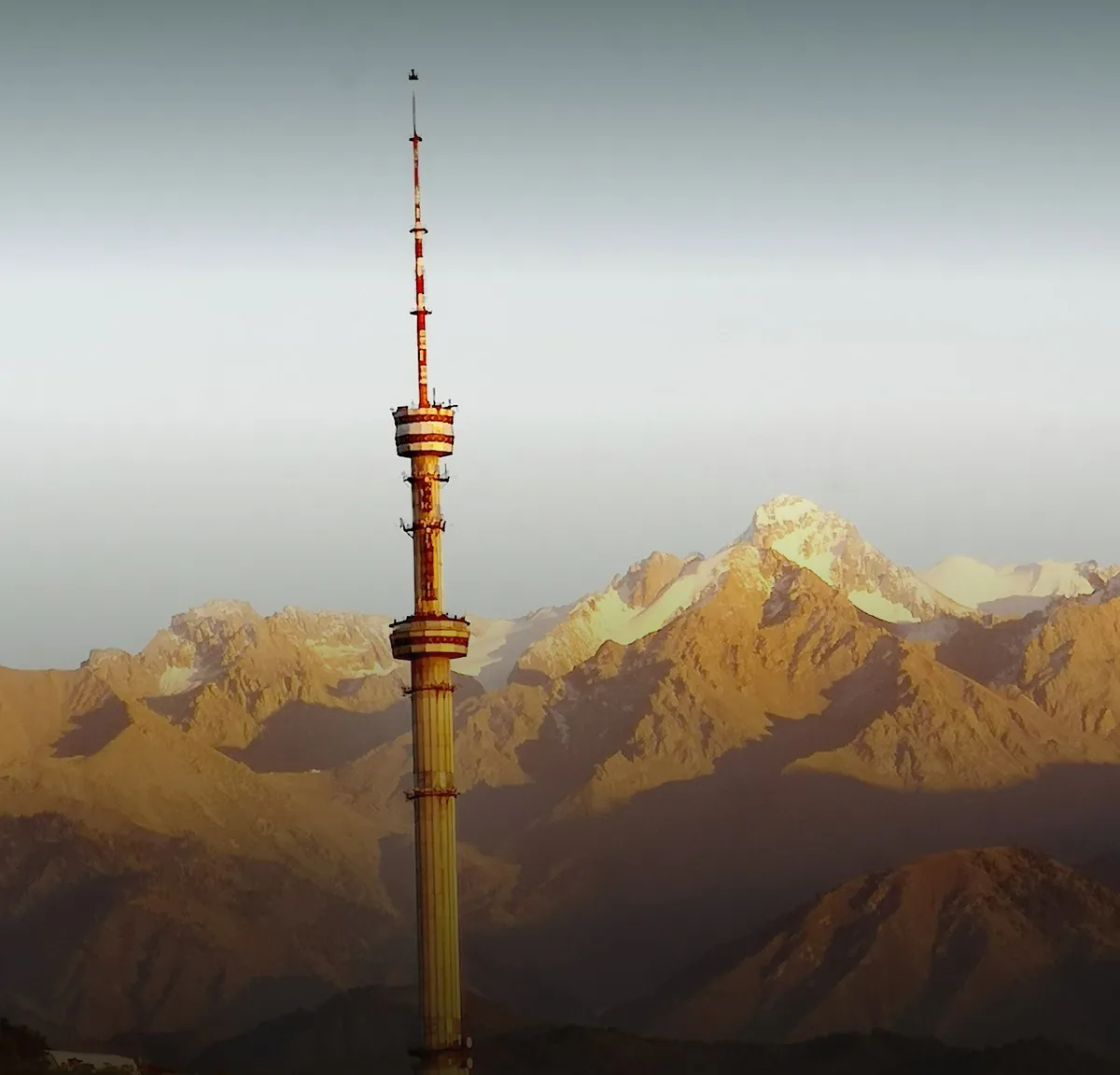 The Kok Tobe TV tower against the mountains at sunset