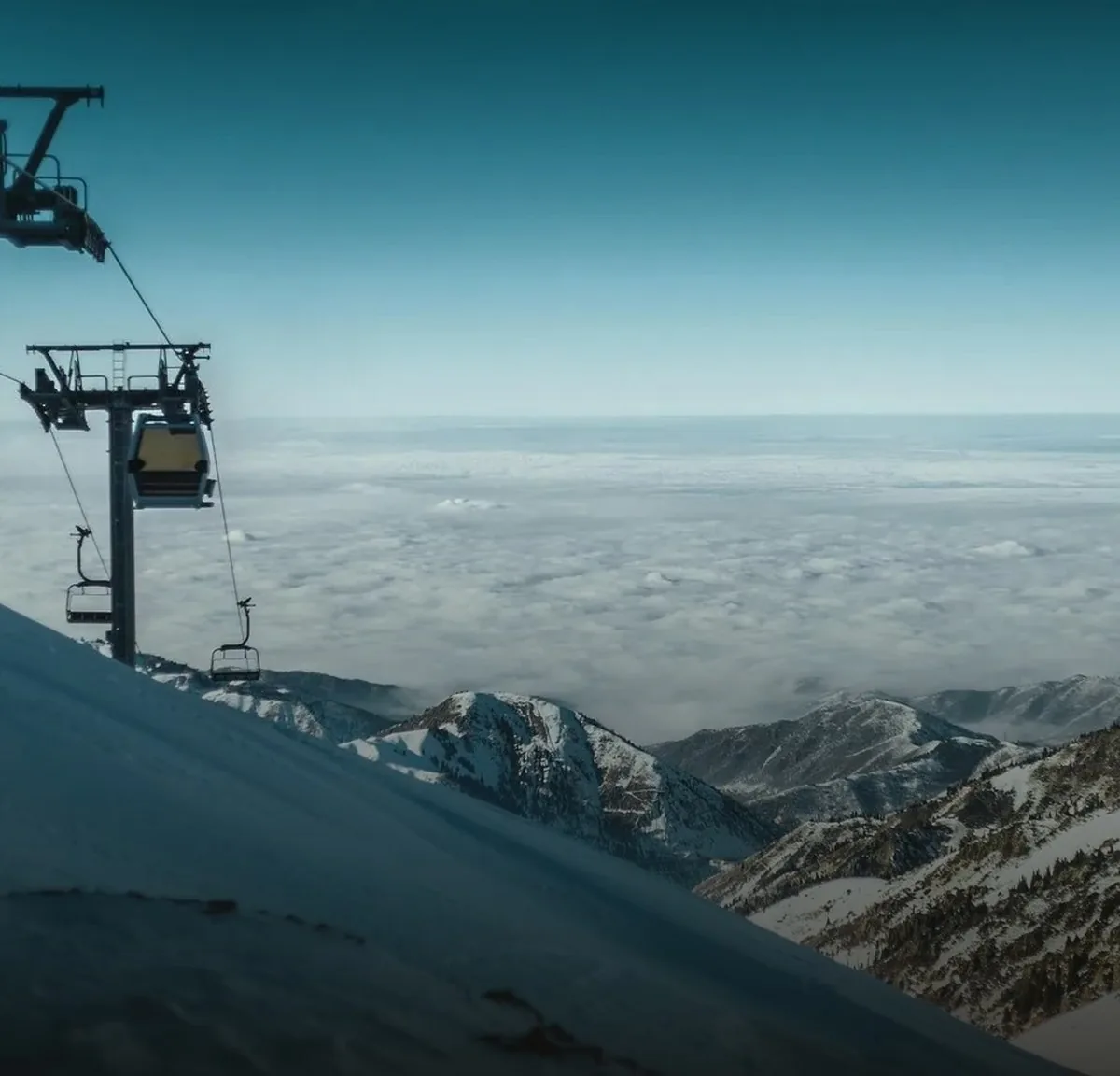 A ski lift above a sea of clouds in the mountains near Shymbulak