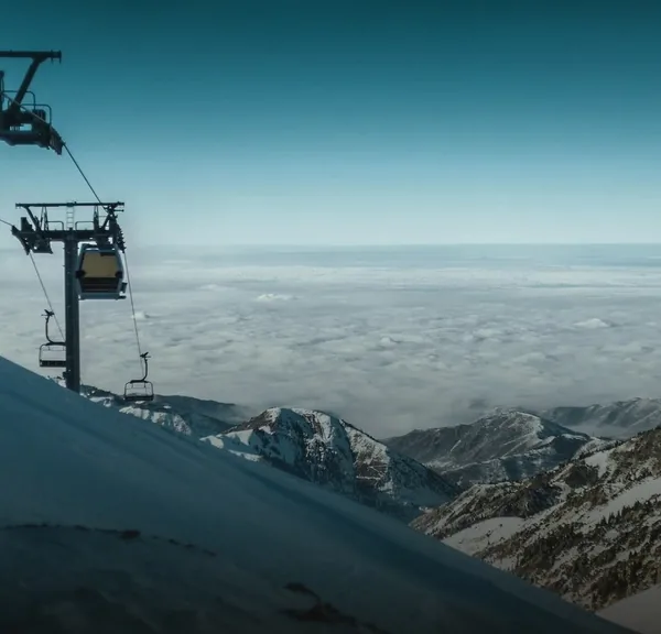 A ski lift above a sea of clouds in the mountains near Shymbulak